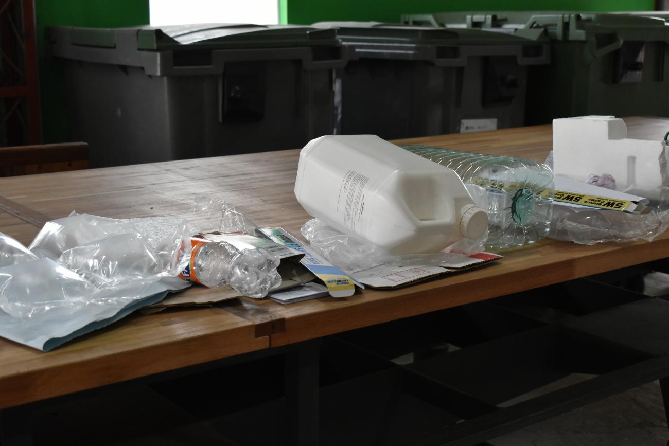 Botellas de plástico, cartón, tapitas y nylon, sobre una mesa.